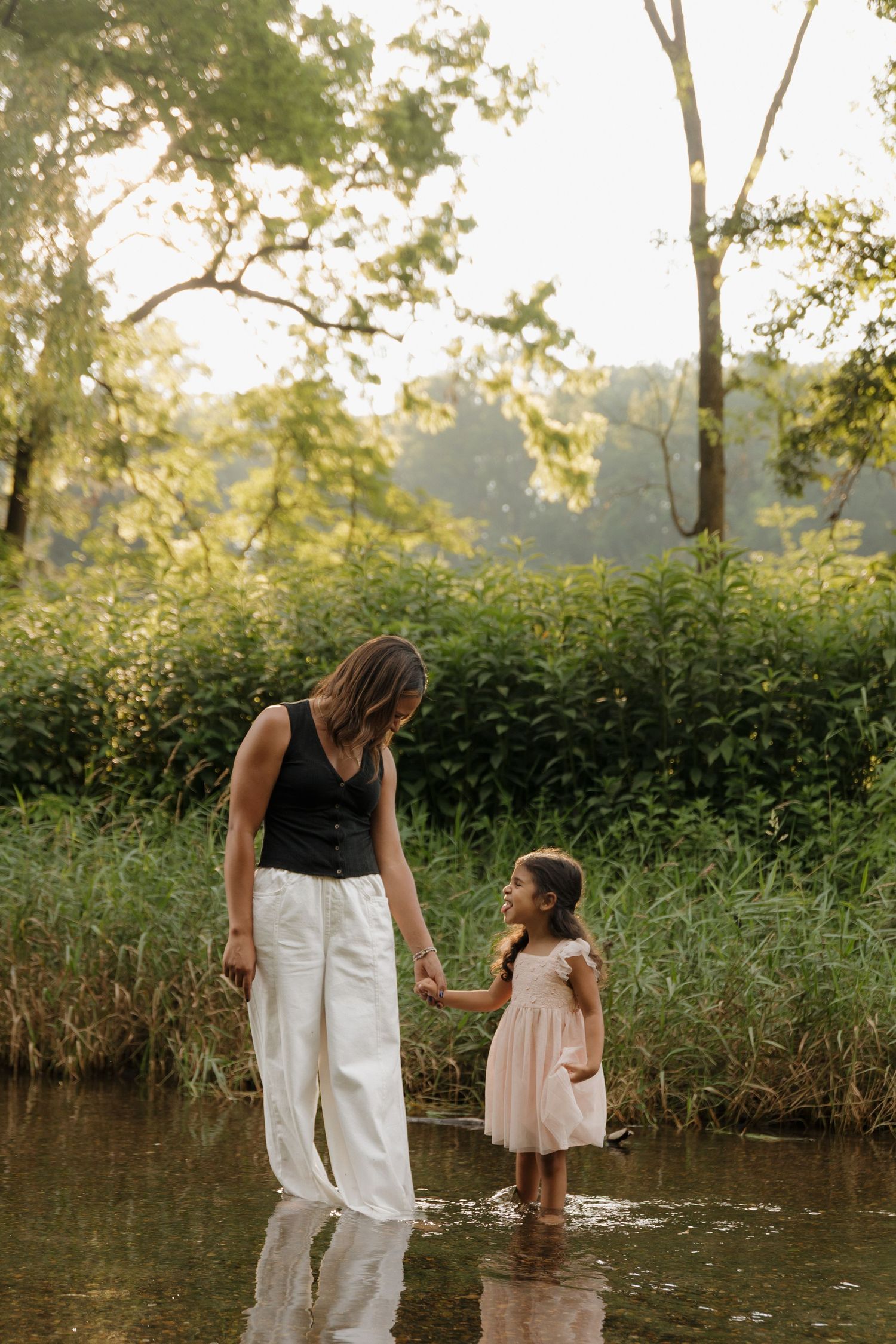 People exploring along a peaceful creek bank in late afternoon sunlight.