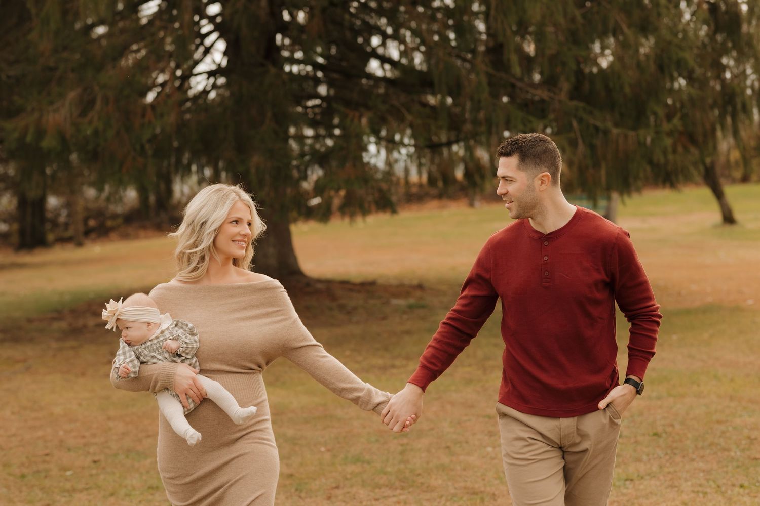 Family in coordinated neutral tones poses together during golden hour outdoor photo session.