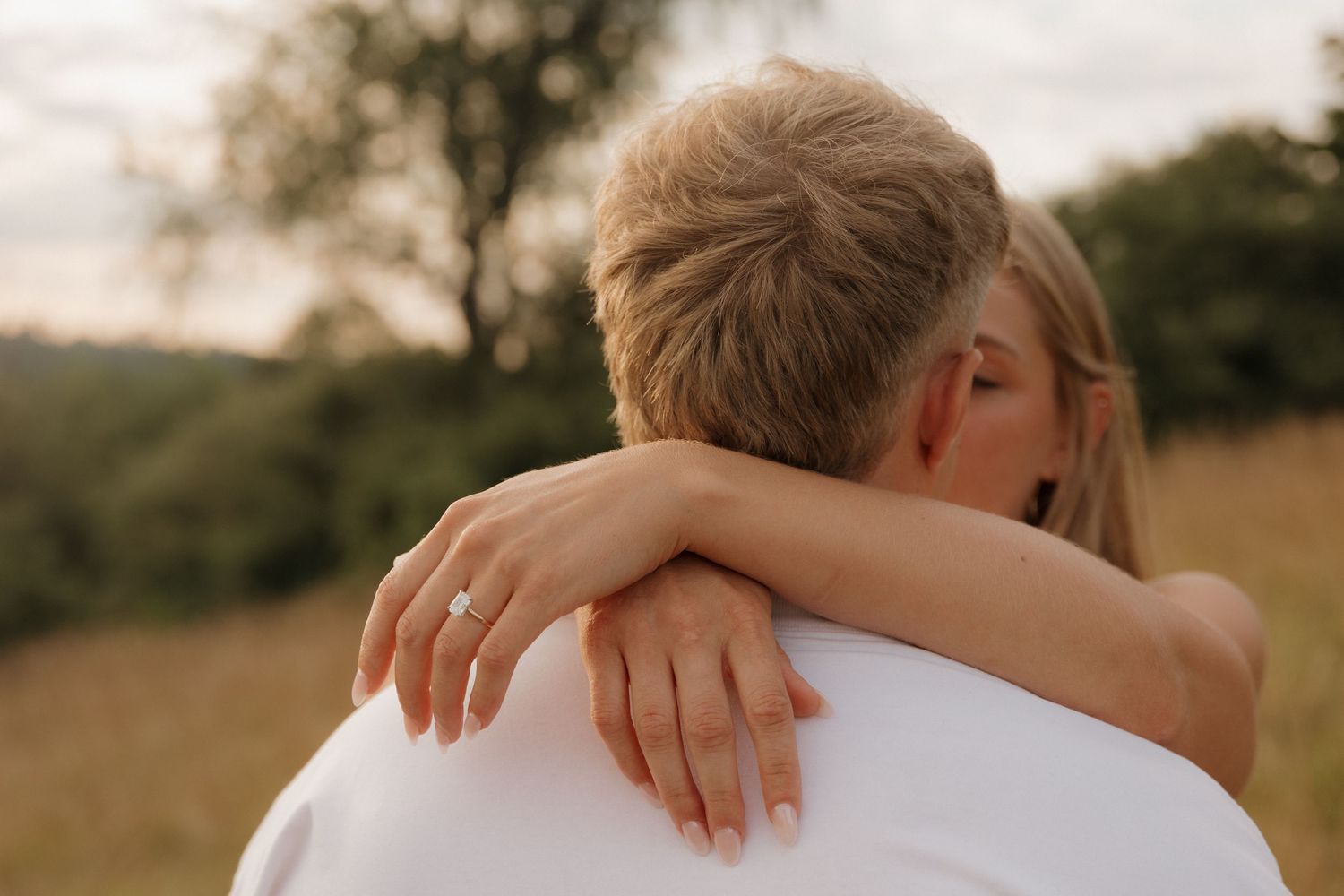 A tender embrace captured in warm sunlight against a natural outdoor backdrop.