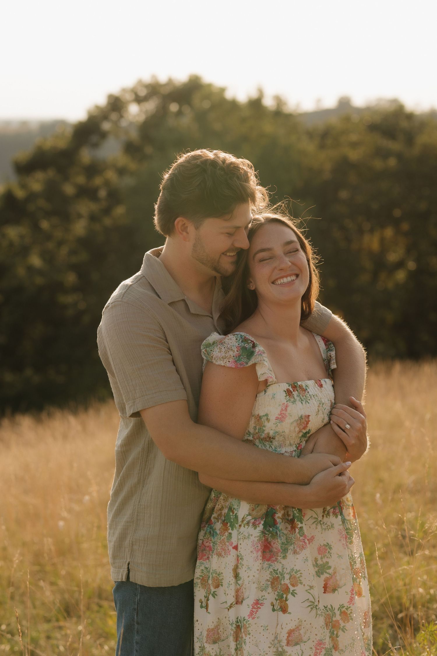 Joyful couple sharing laughter and embraces in a sun-drenched field at golden hour.