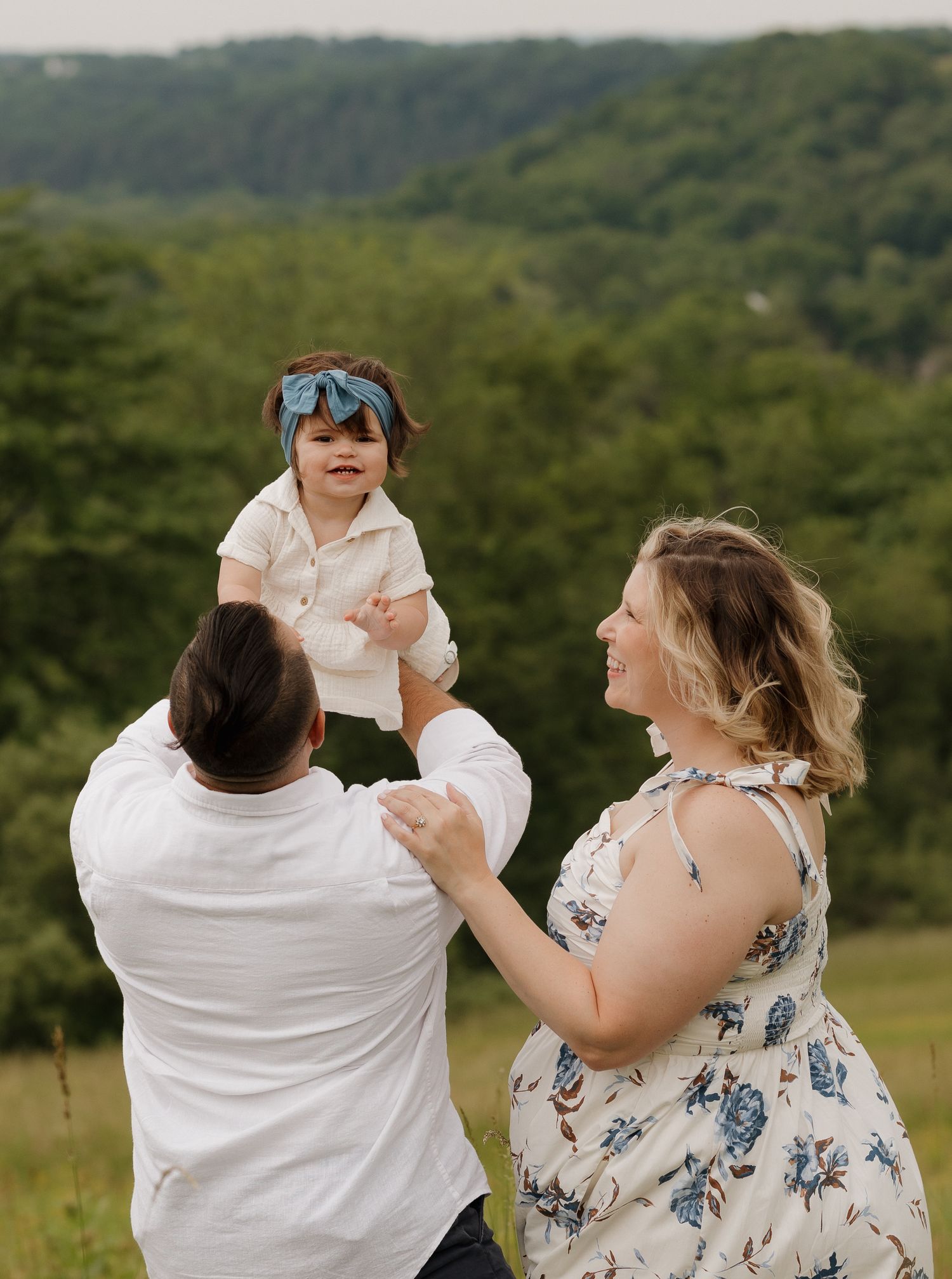 Couple playfully dancing together in sunny meadow with mountain backdrop.