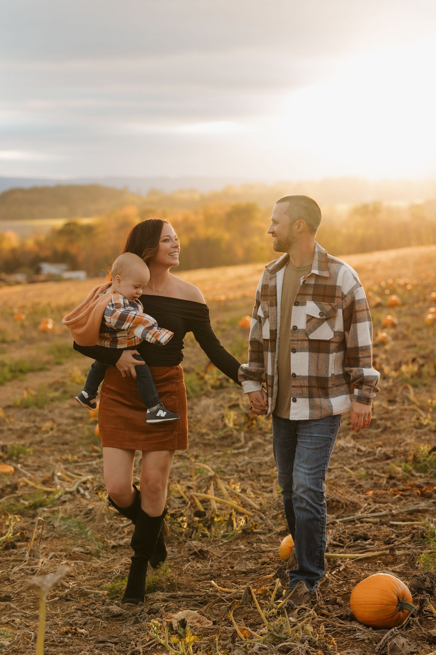 Family exploring pumpkin patch together during autumn sunset. Fall family session
