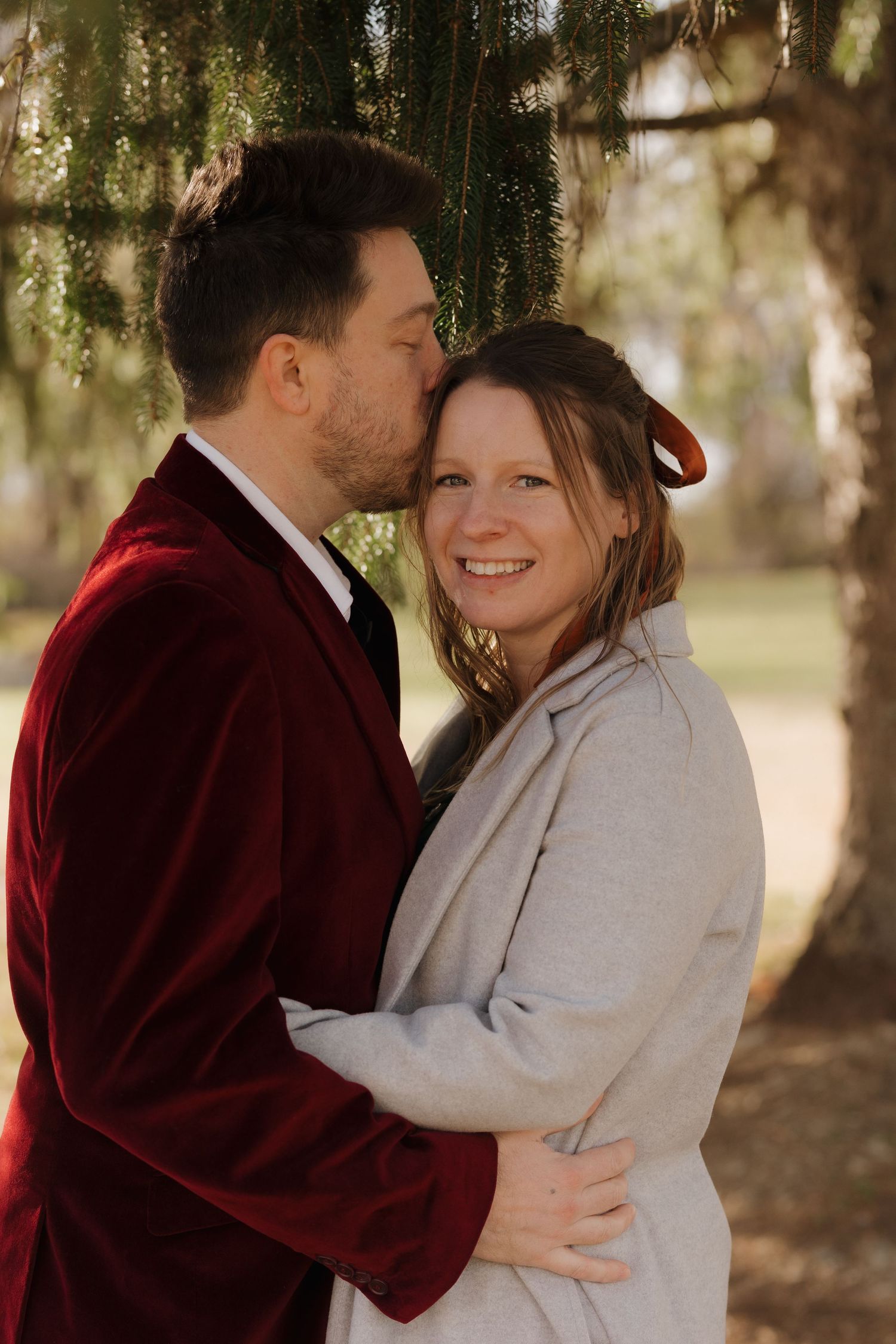 Romantic outdoor winter photoshoot under evergreen trees.