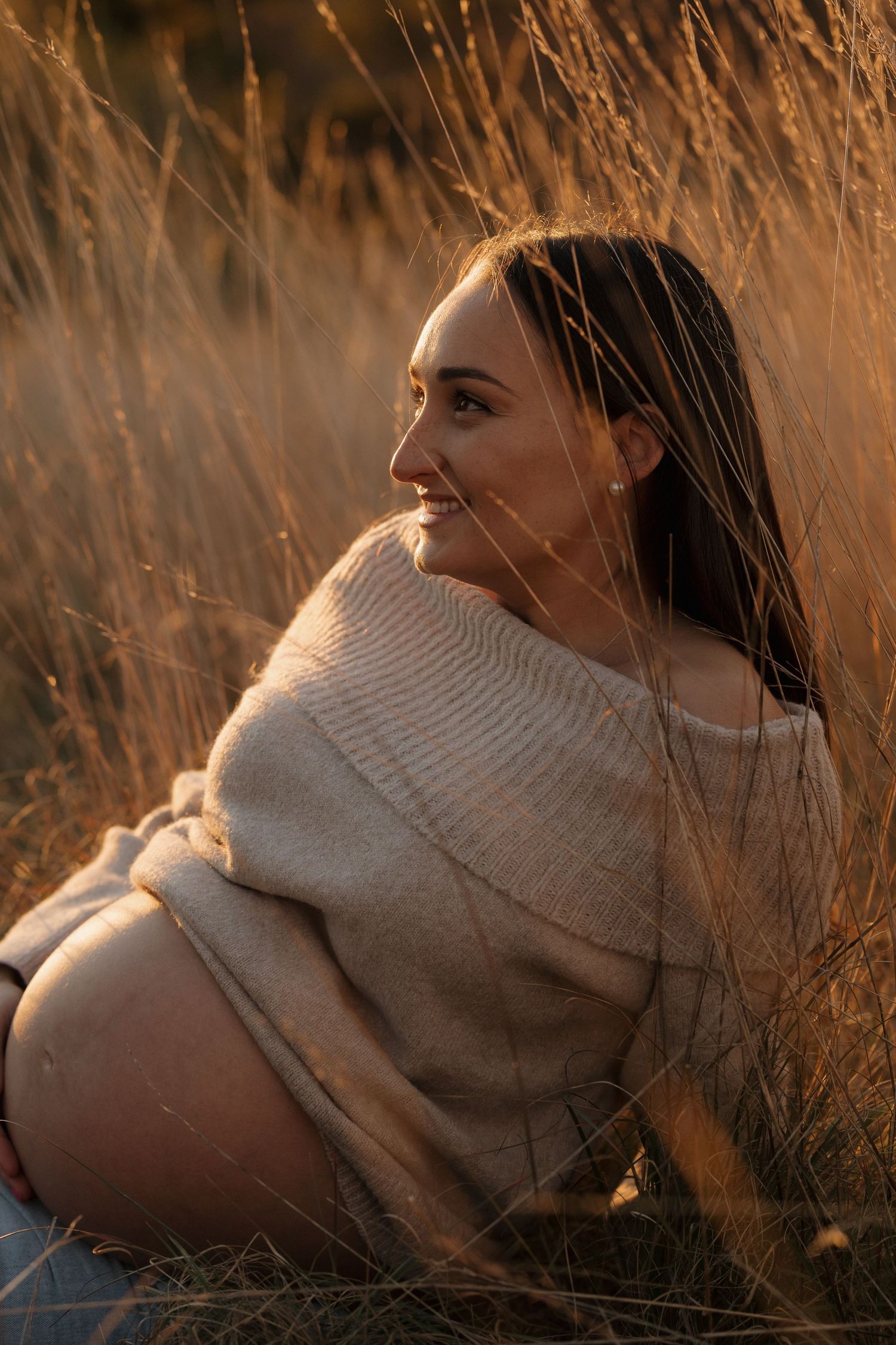 A person resting in tall grass during golden hour with sun flares.
