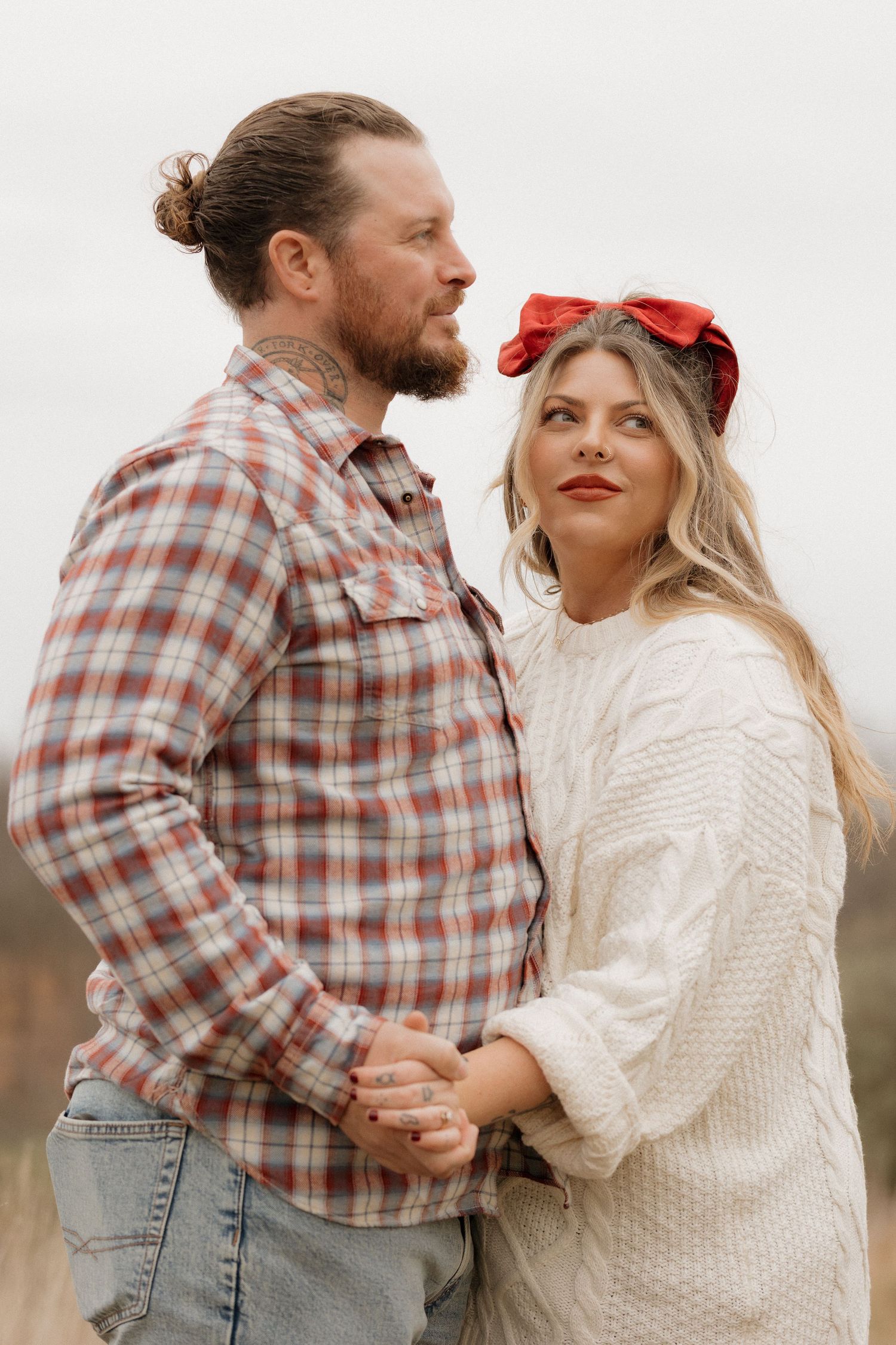 Couple in casual attire holding hands during countryside photo session.