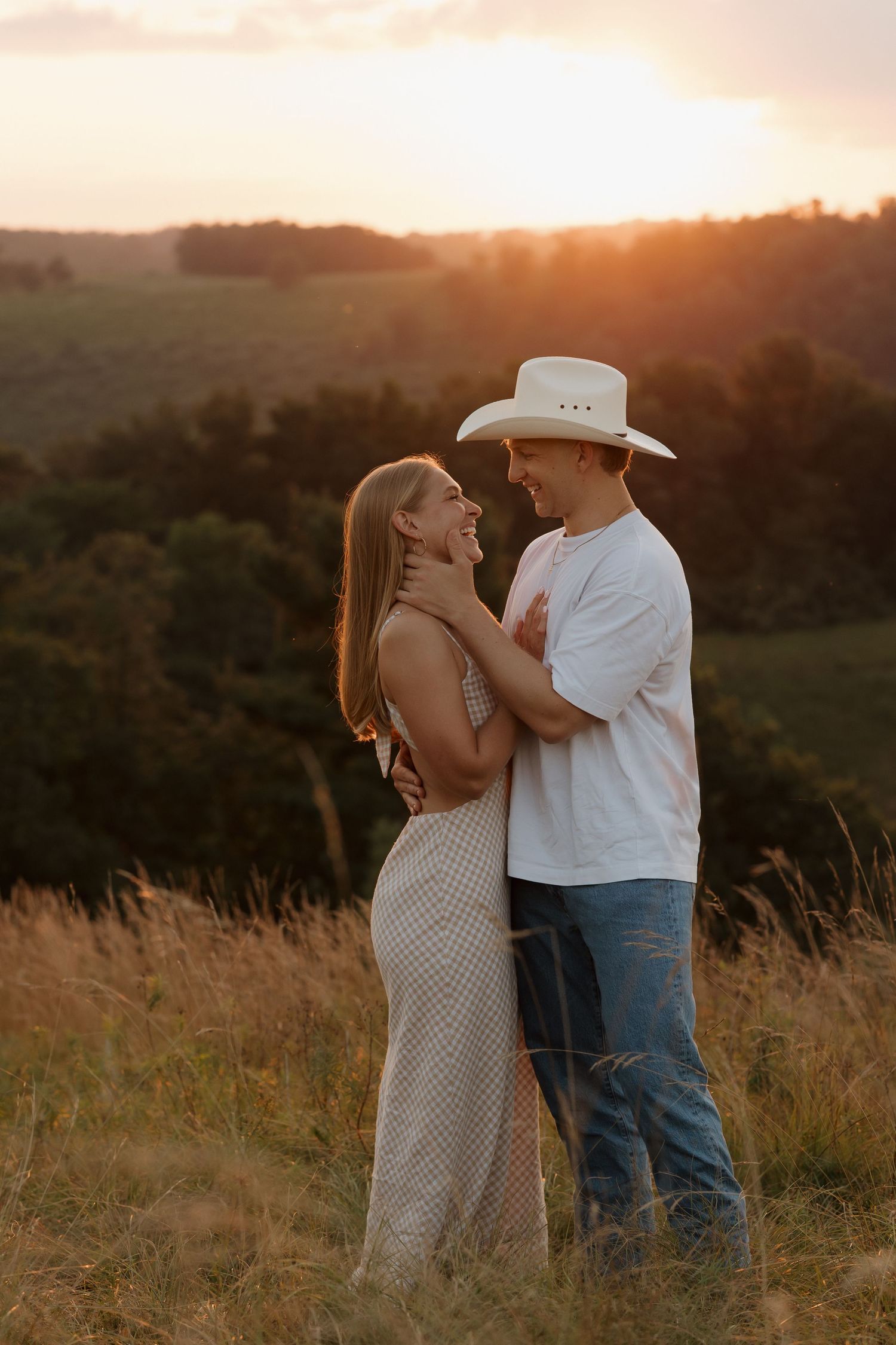A couple embraces in a golden field during sunset creating a romantic silhouette against the warm sky.