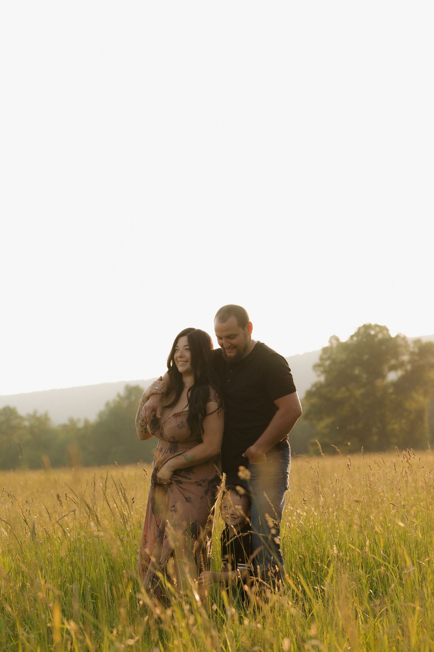 Playful interaction between people in a sunlit meadow with mountains behind.
