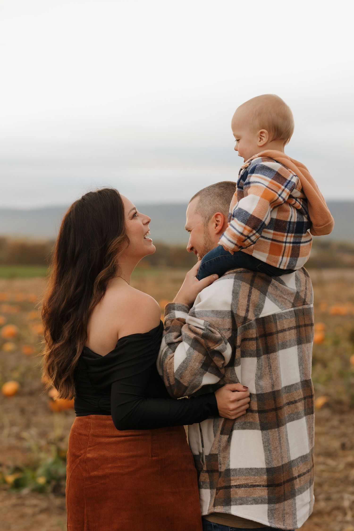 Family shares playful moments together in a rustic field setting.