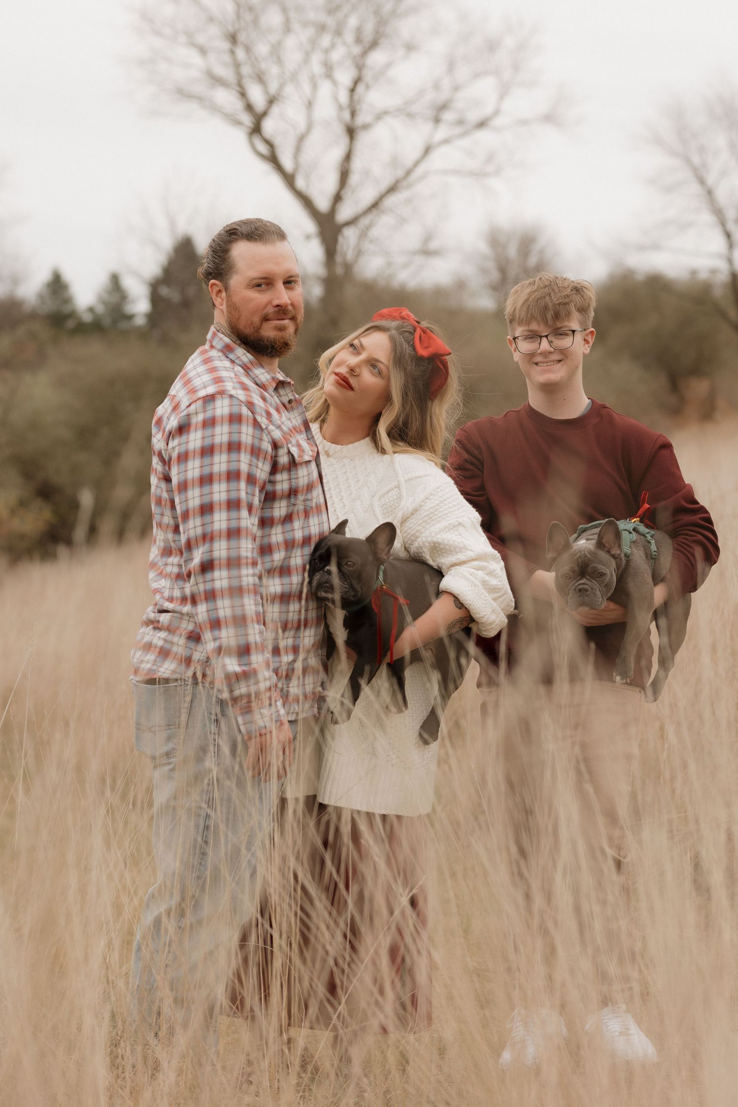 Family portrait in tall grass field with two French Bulldogs.