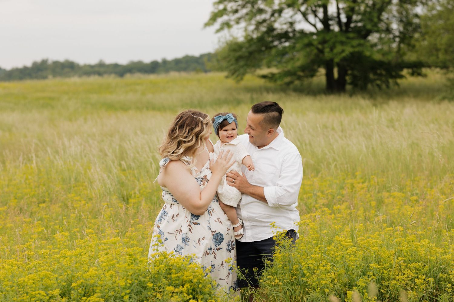 Couple dancing in sunny wildflower meadow wearing white and floral outfits.