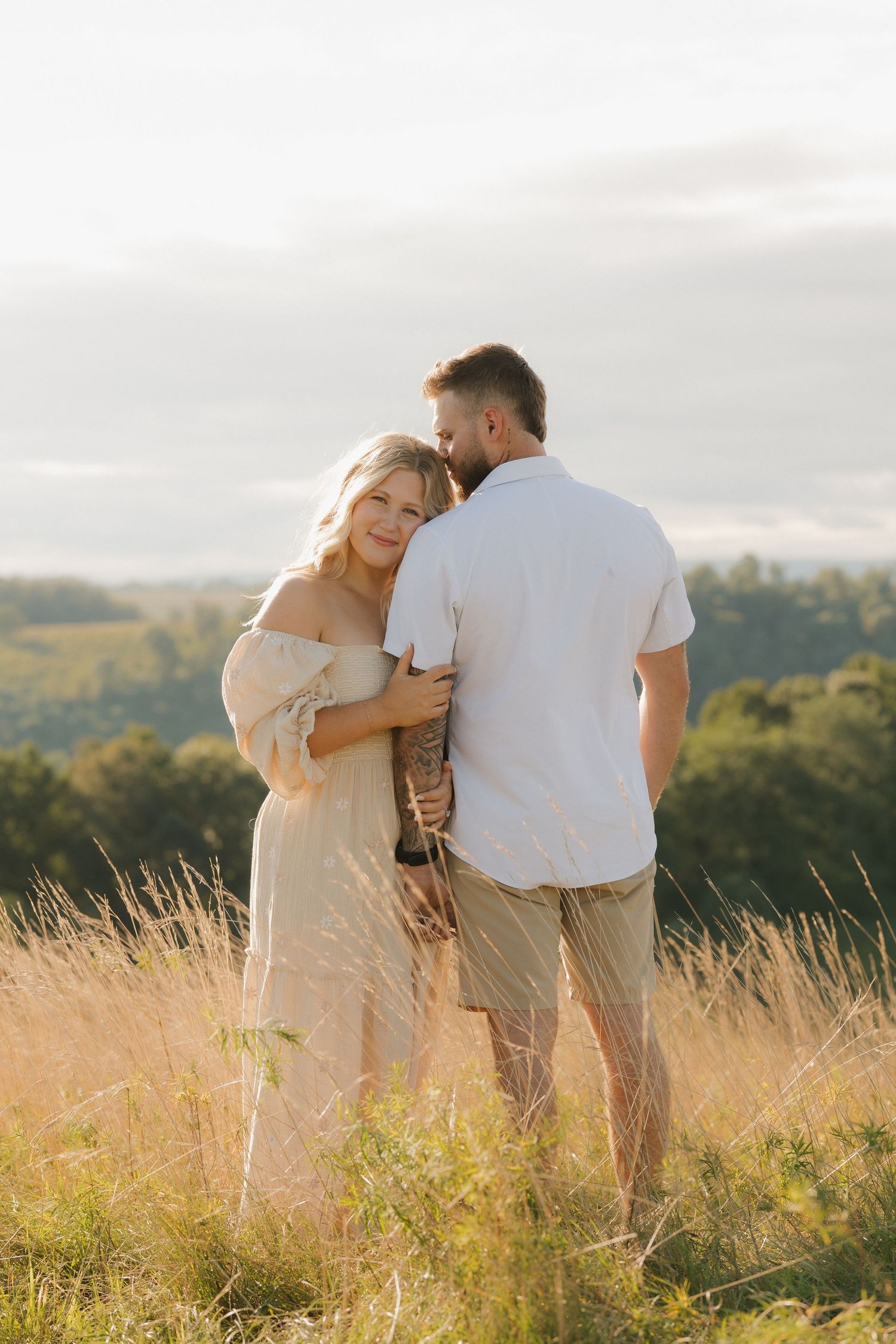 Couple walking through tall grass field during golden hour sunset.