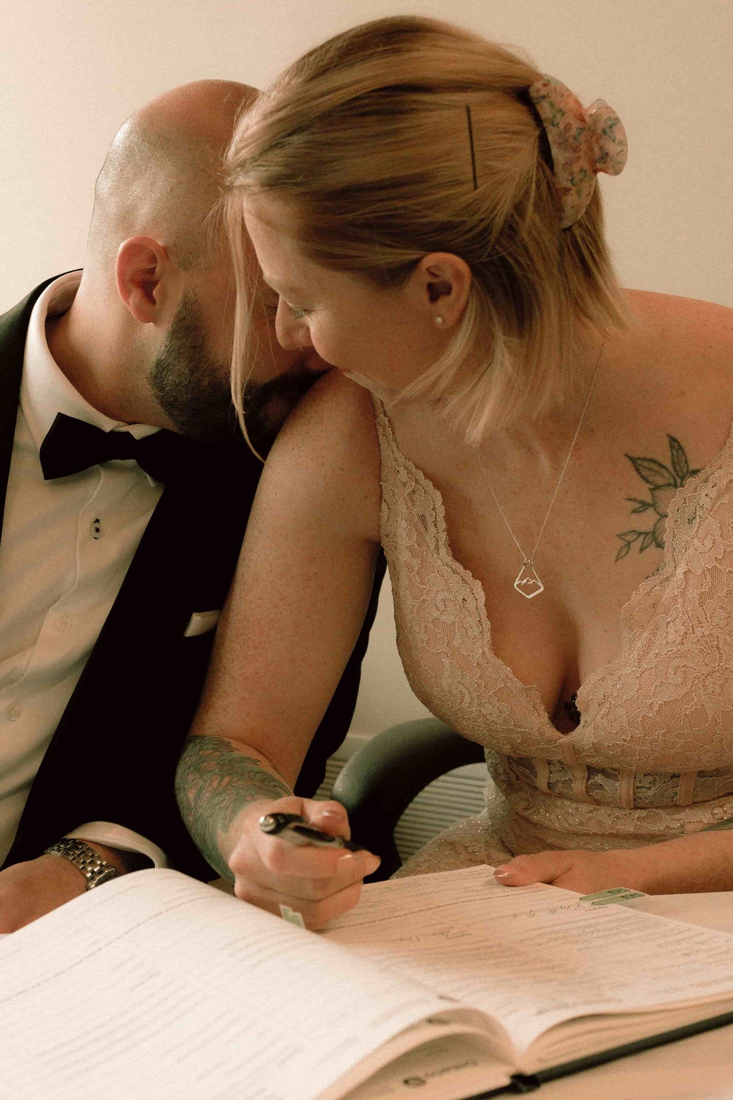 Couple signing marriage documents at City Hall while sharing an intimate moment