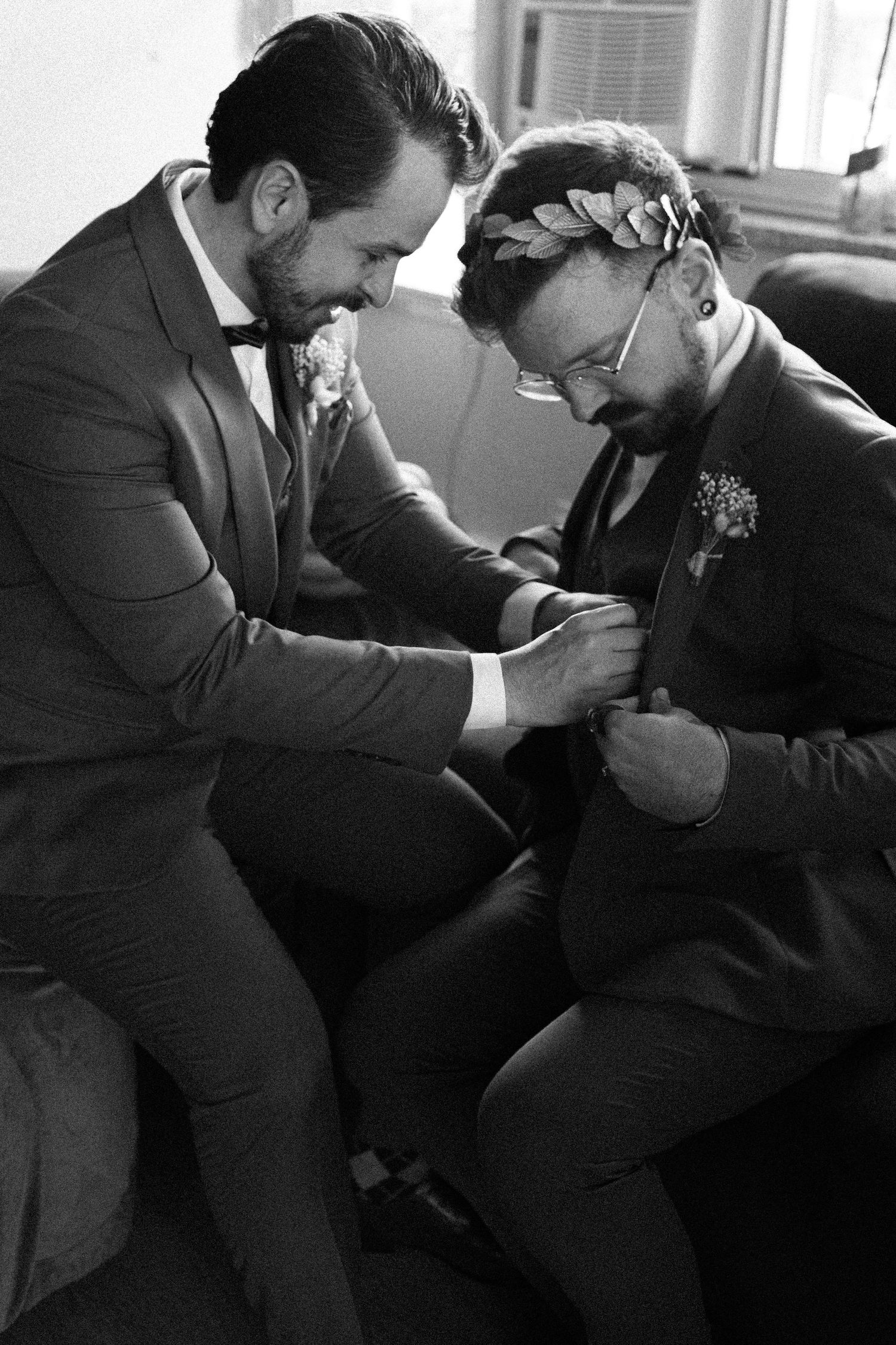 Groom placing a memorial boutonniere pin on the other groom’s blazer during an emotional Toronto wedding moment