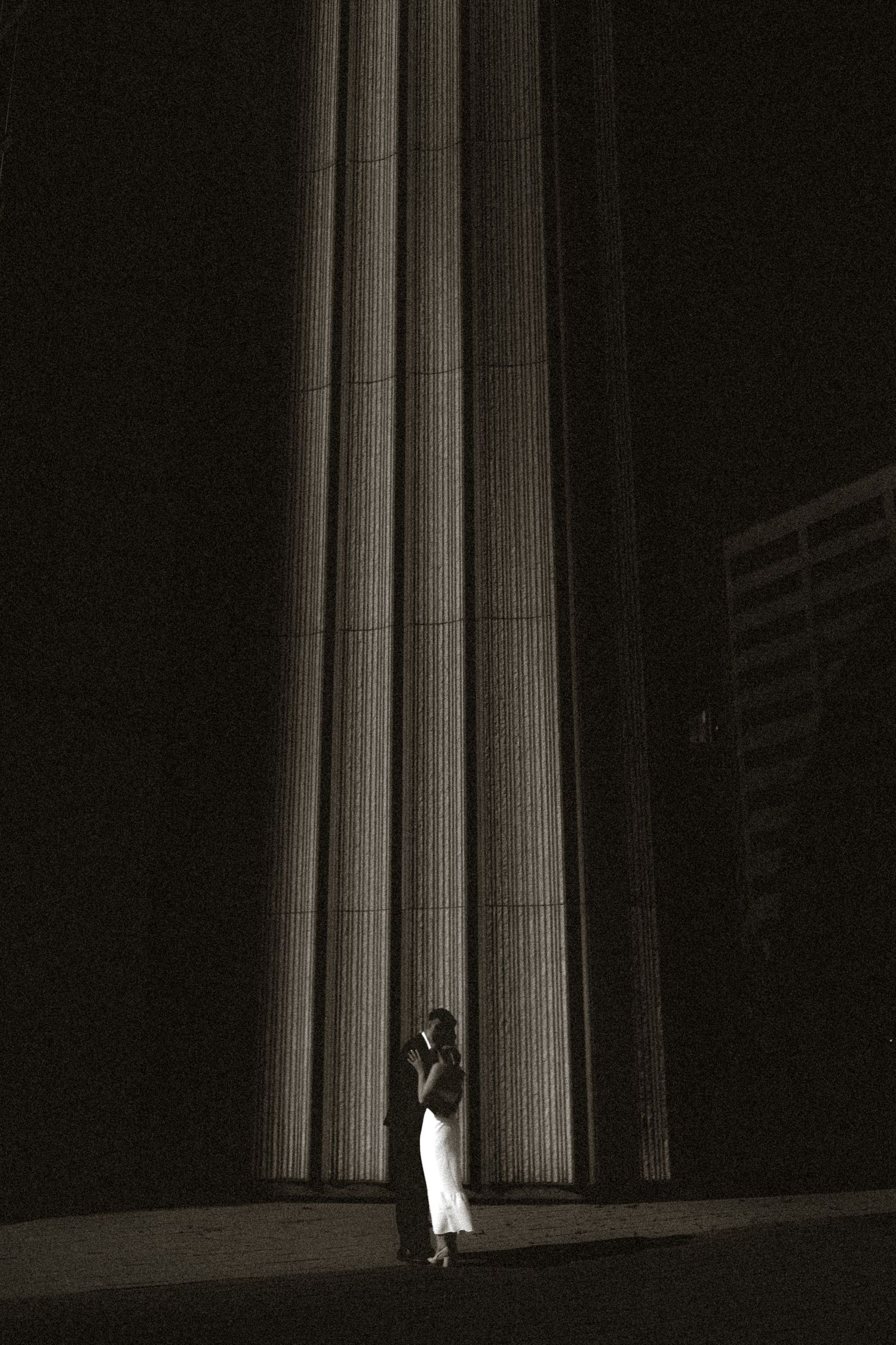 Black and white Toronto City Hall engagement photo of a couple kissing, with strong shadows and a minimalist, brutalist composition