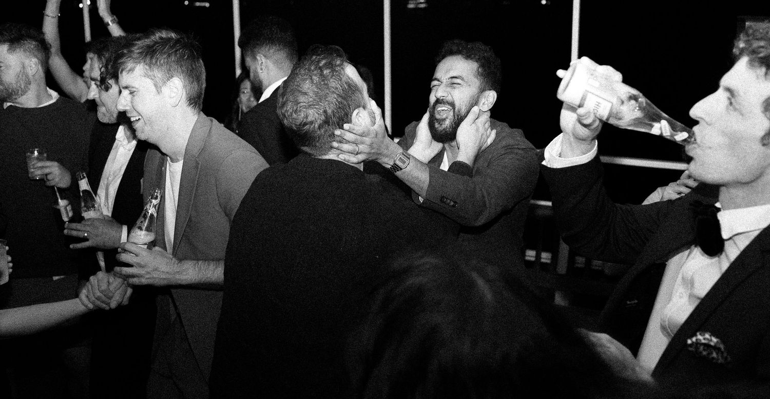 Candid Toronto wedding photo of groom and friend sharing a playful, emotional moment while singing and laughing together