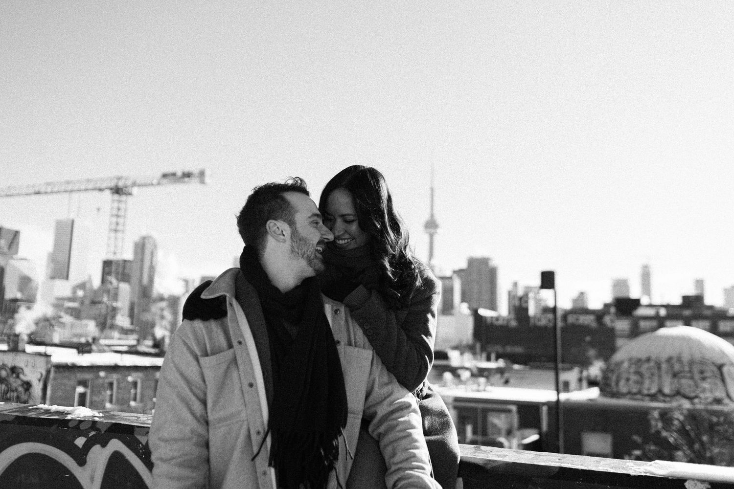 Toronto engagement session at Kensington Market with the city skyline in the background, couple leaning in together