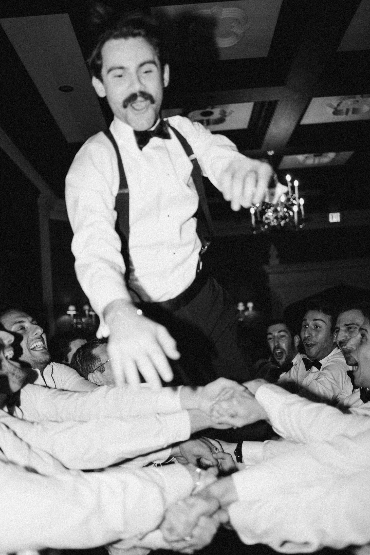Groom being tossed by groomsmen during jewish hora at Old Mill Toronto Fall wedding