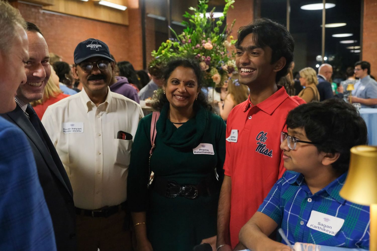 Group of people smiling and socializing at an indoor gathering or reception event.