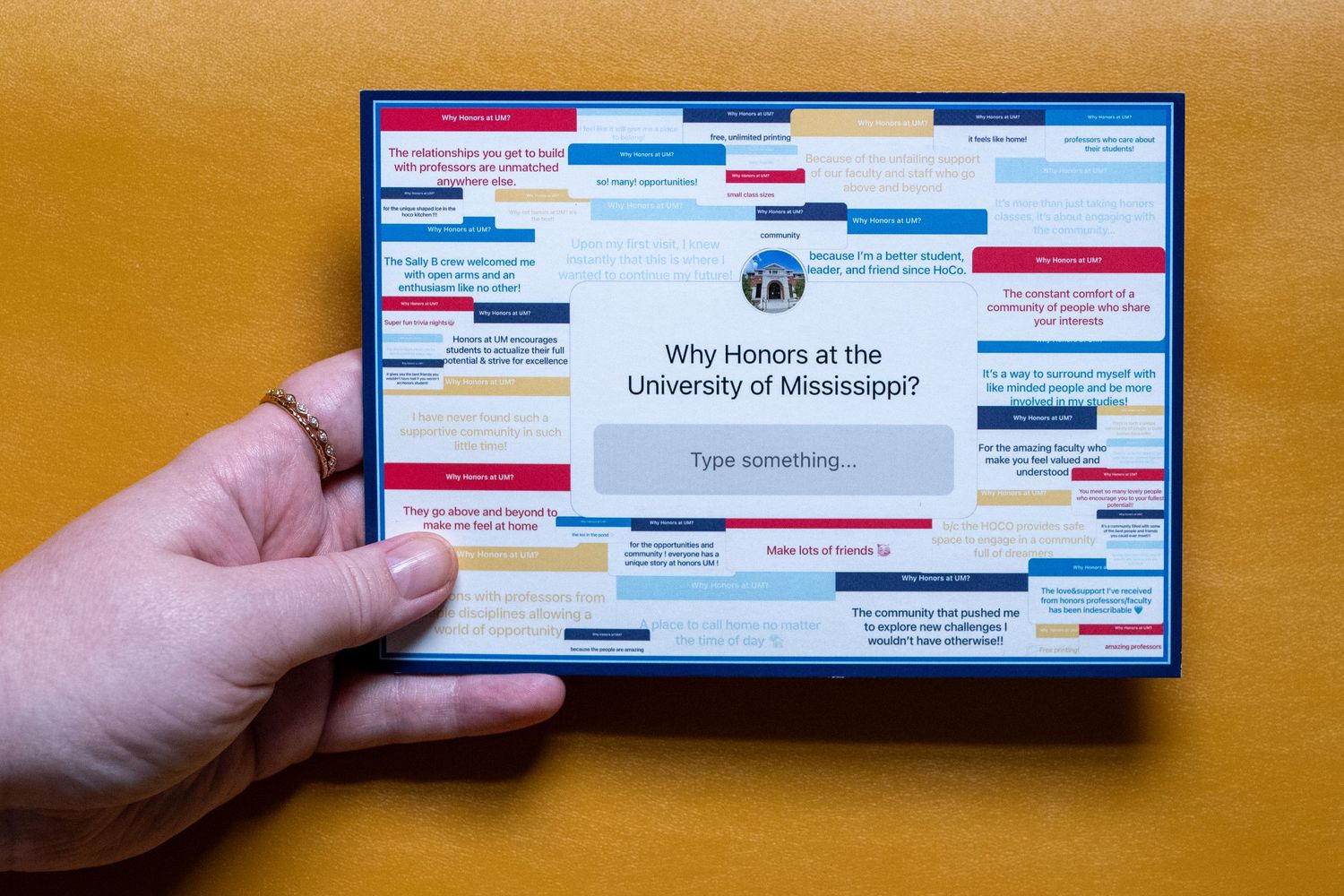 Hand holding a card displaying 'Why Honors at the University of Mississippi?' with colorful text snippets on a wooden surface.