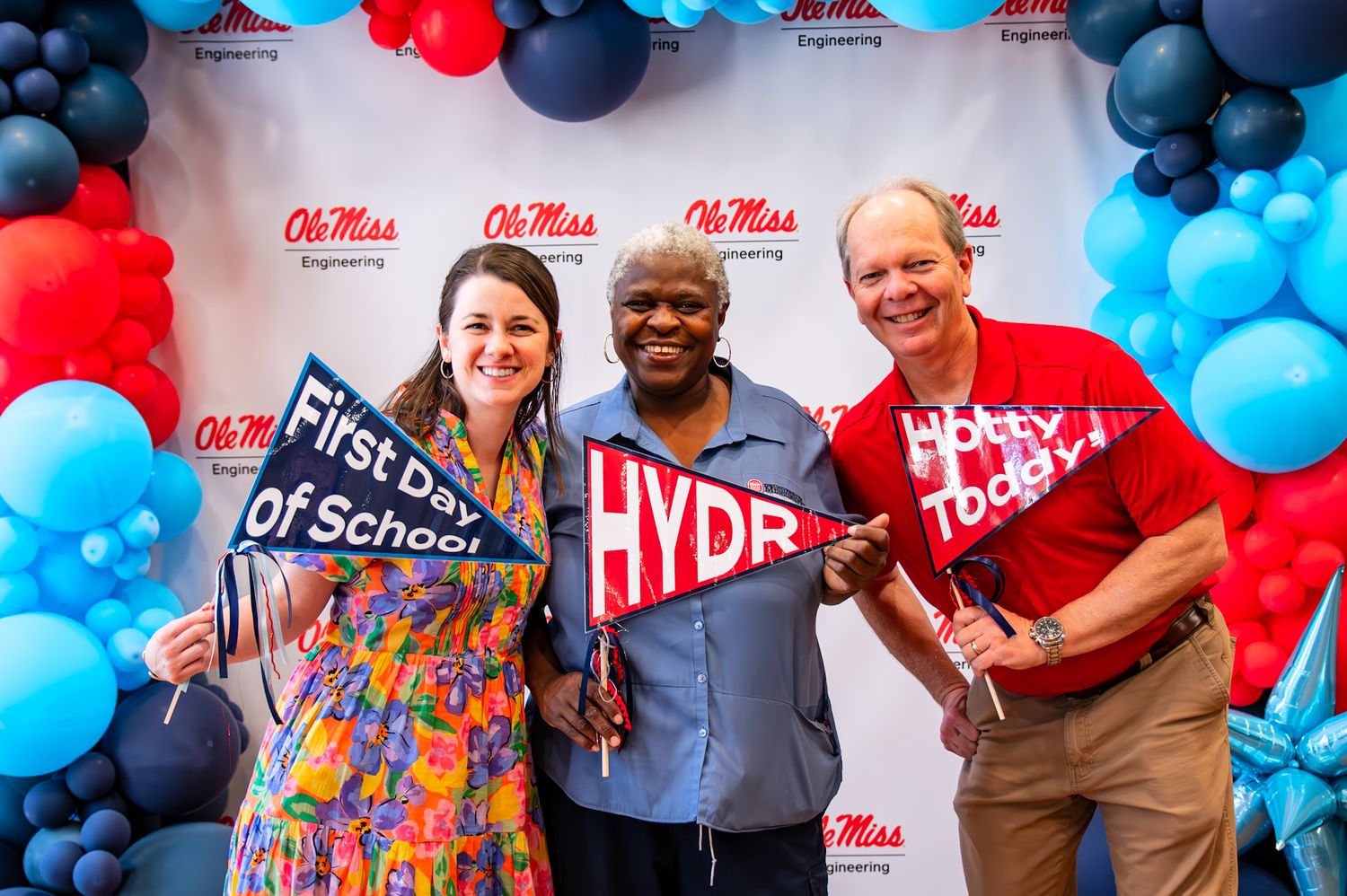 Group photo with red and blue balloon arch decorations at Ole Miss campus event celebration.