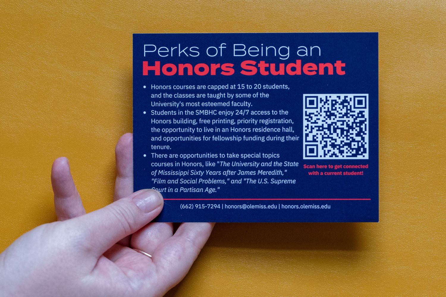 Hand holding a card listing Perks of Being an Honors Student at SMHC with a QR code for more information.