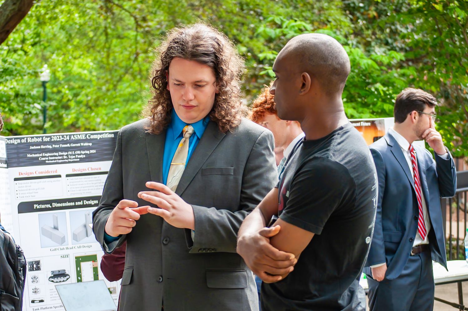 Two professionals discussing a research poster display at an outdoor academic conference event.