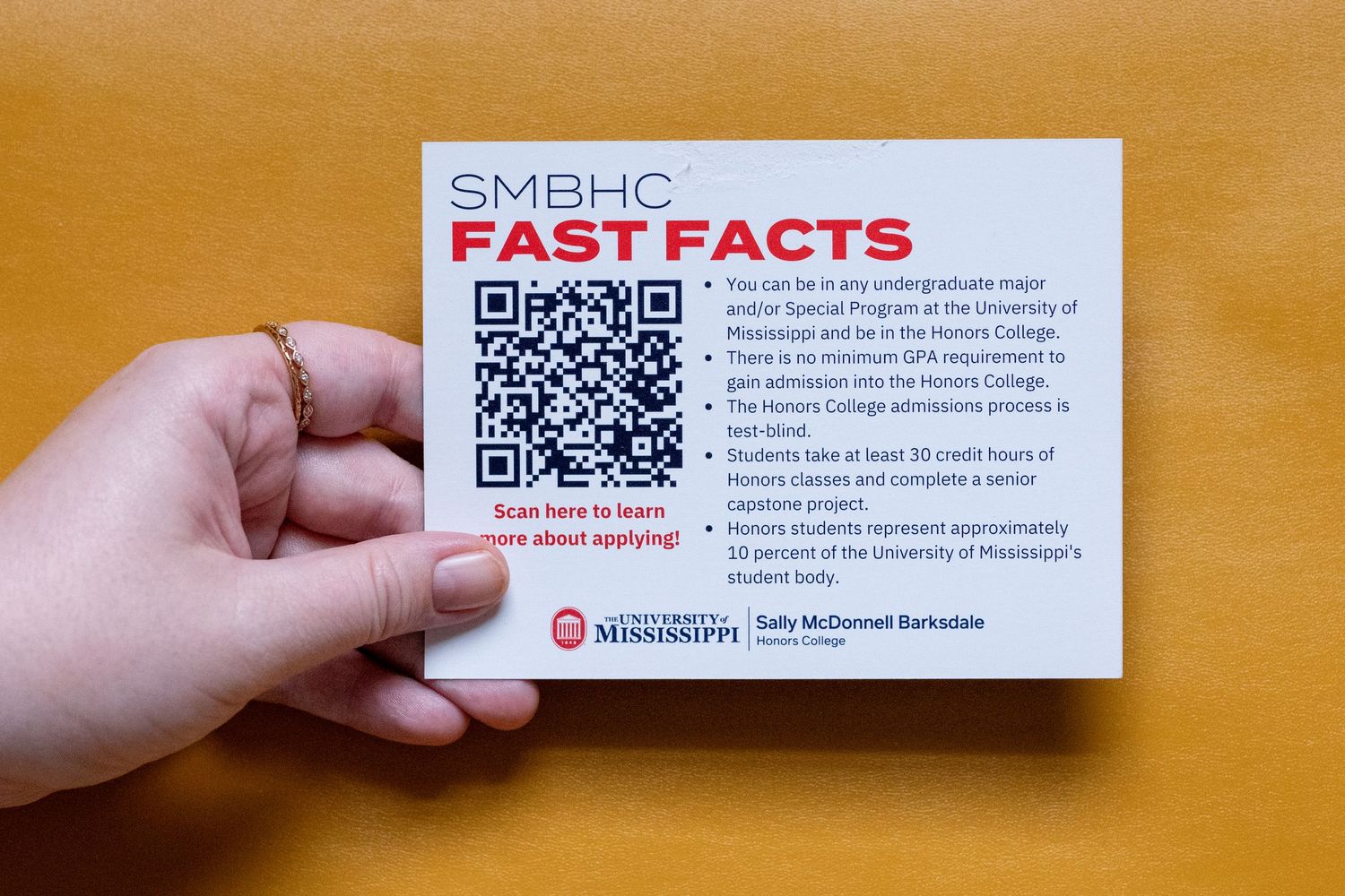 Hand holding SMBHC Fast Facts card with QR code from University of Southern Mississippi Honors College.