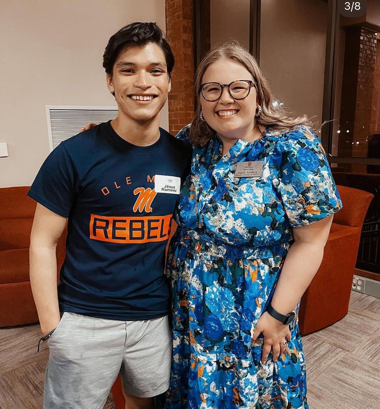 Two smiling people pose together, one wearing an Ole Miss Rebels shirt, at an indoor social gathering.