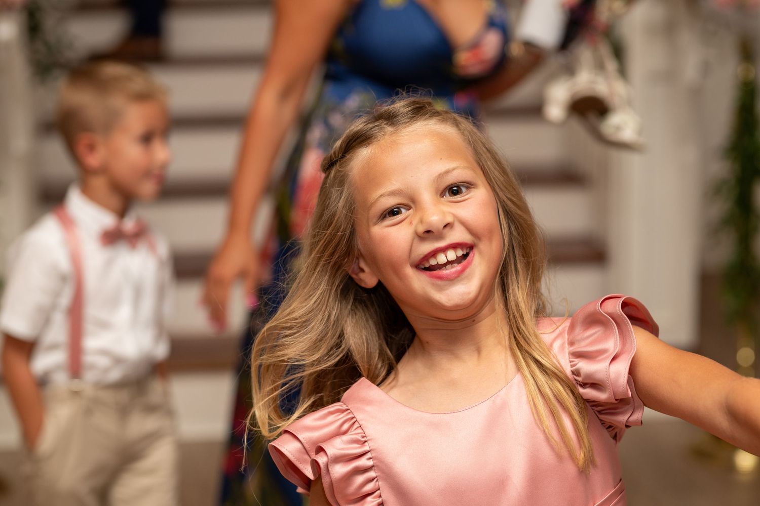 A person wearing a pink dress dances and smiles during what appears to be a celebration or party.