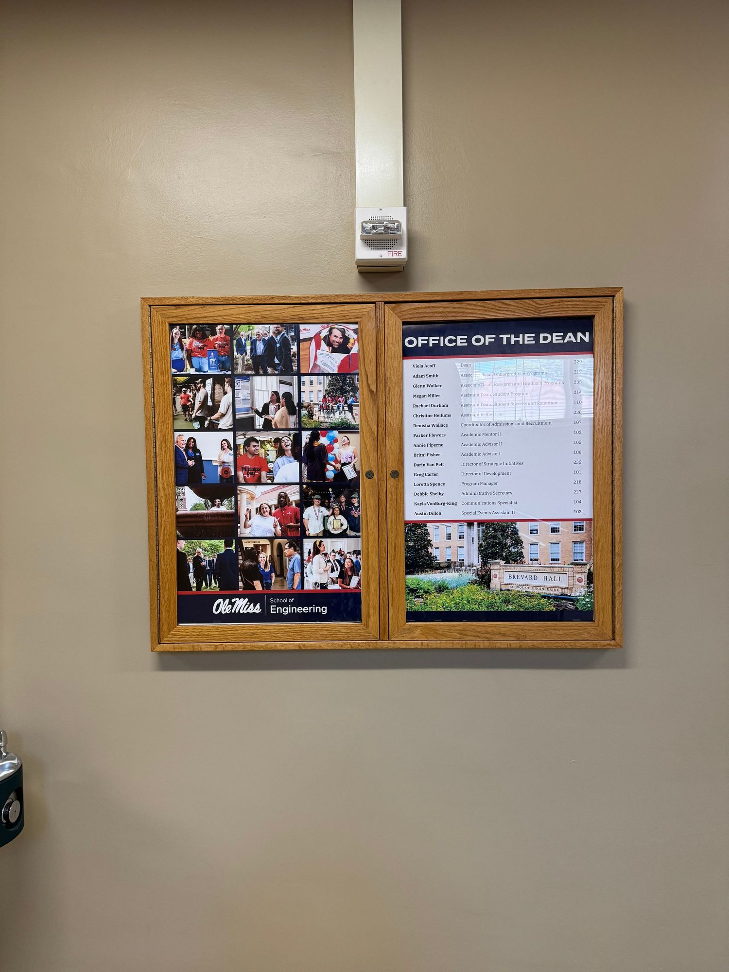 A bulletin board displaying Ole Miss School of Engineering photos and Office of the Dean directory mounted on a beige wall.