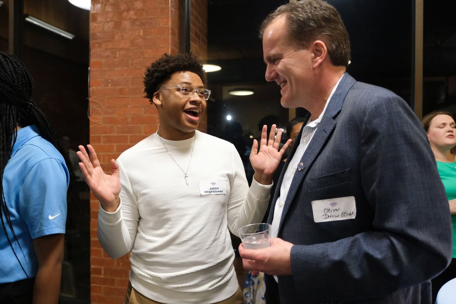 Two men laughing and gesturing animatedly during a casual networking event indoors.