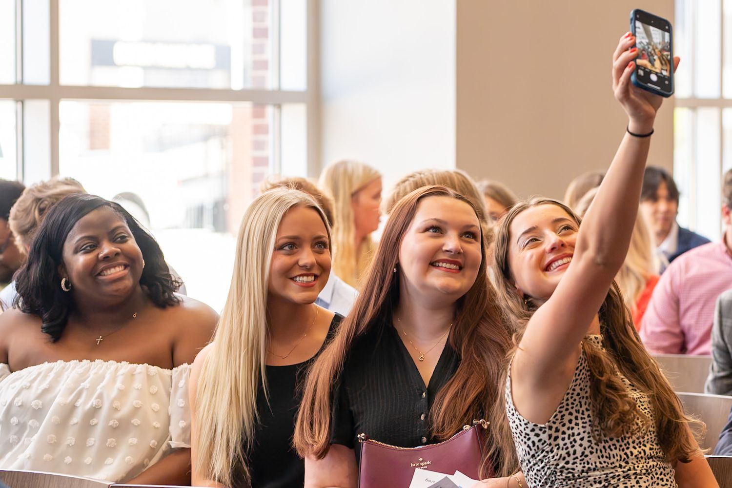 A group of friends smile together while taking a selfie at a social gathering.