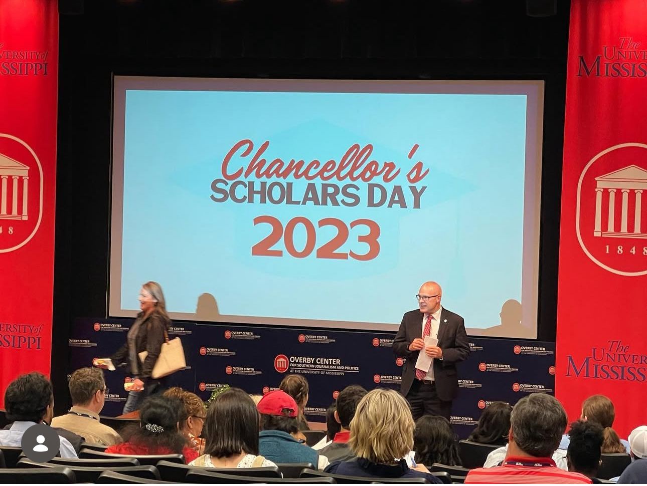 Two speakers present at Chancellor's Scholars Day 2023 event on a red-draped stage at the University of Mississippi.