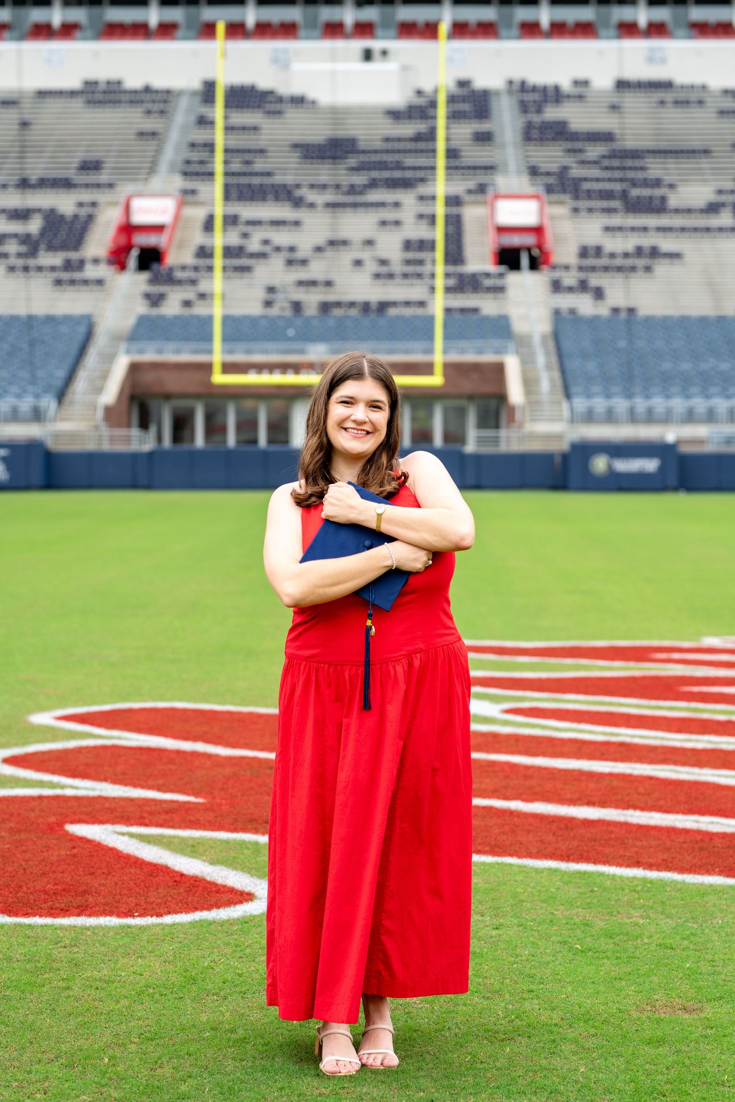 Empty football stadium with yellow goal posts and red endzone markings on the field.