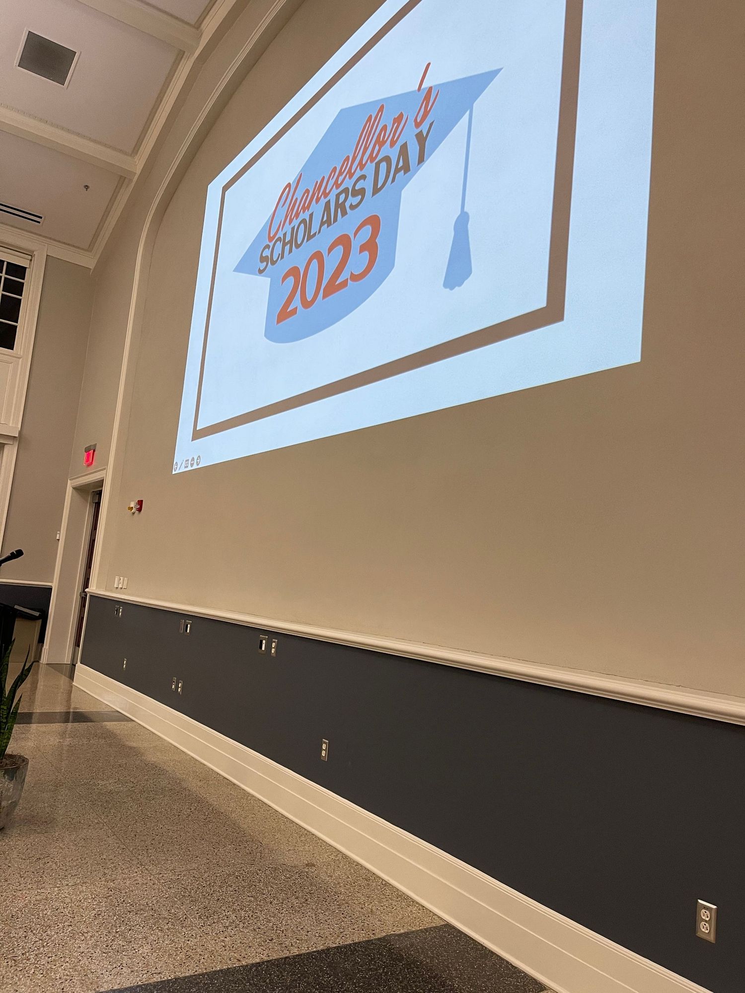 Projected screen displaying Chancellor's Scholars Day 2023 logo with graduation cap in a university lecture hall.