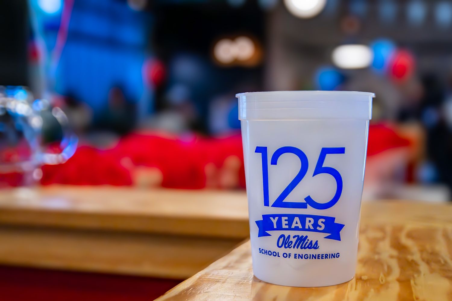 Ole Miss School of Engineering 125th anniversary commemorative plastic cup displayed on a wooden surface.