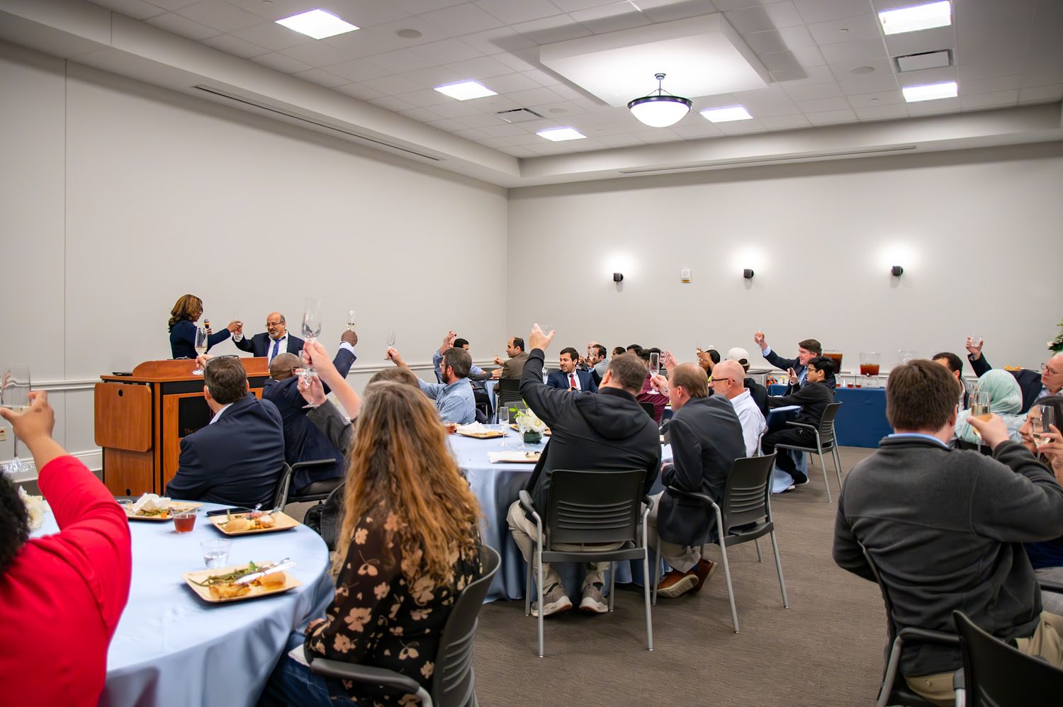 Business professionals attend a conference meeting in a modern conference room with fluorescent lighting and white walls.
