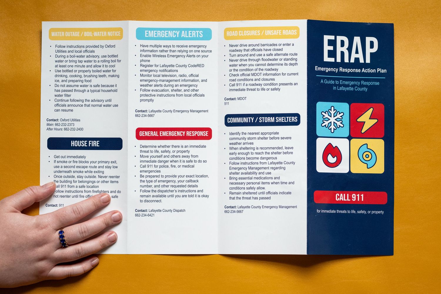 A hand holds open a tri-fold ERAP Emergency Response Action Plan brochure on a wooden table.