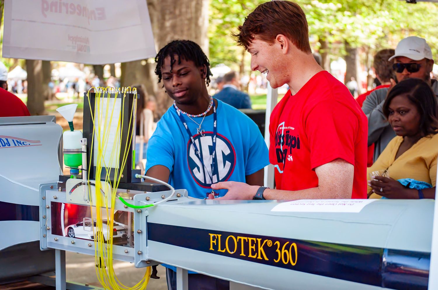 Students working together at a Plotek 360 booth during an outdoor campus event.