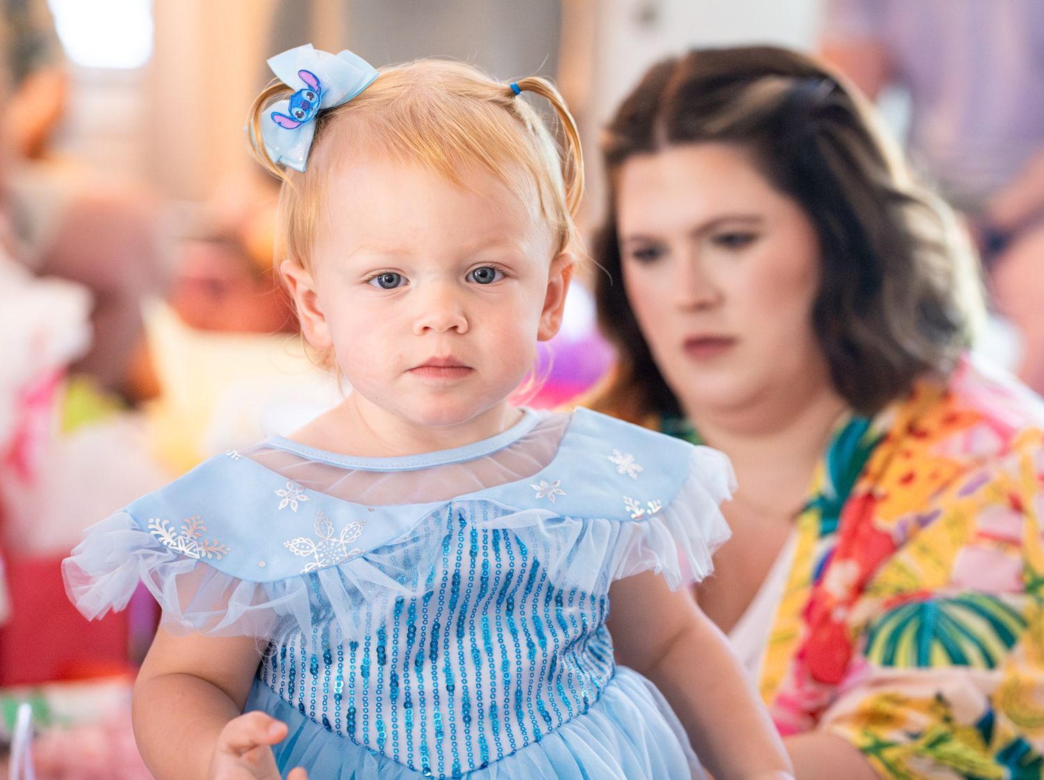 A row of children in blue and white striped outfits play together at a colorful indoor event.