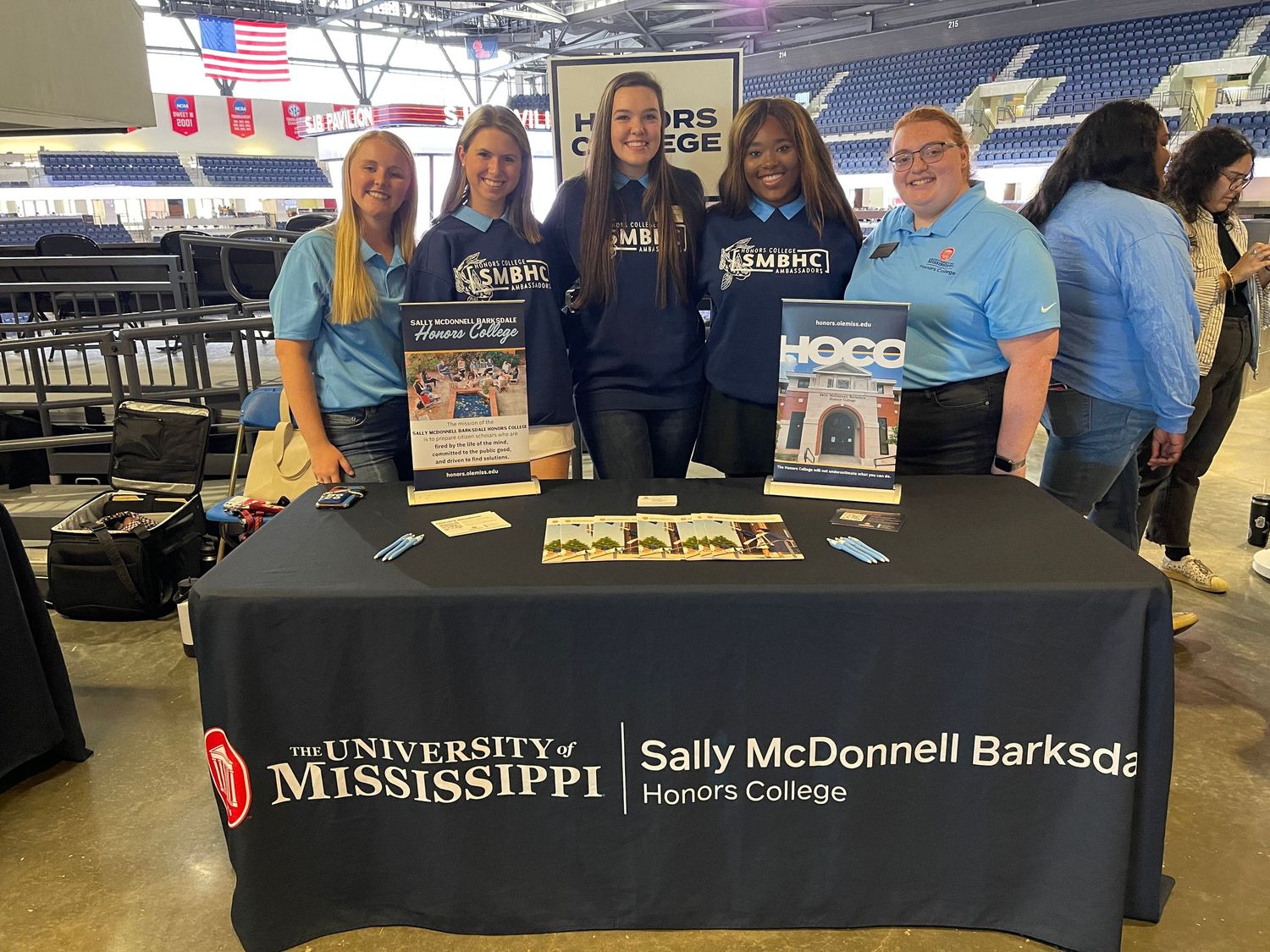 Five students pose at University of Mississippi Sally McDonnell Barksdale Honors College recruitment table at college fair.