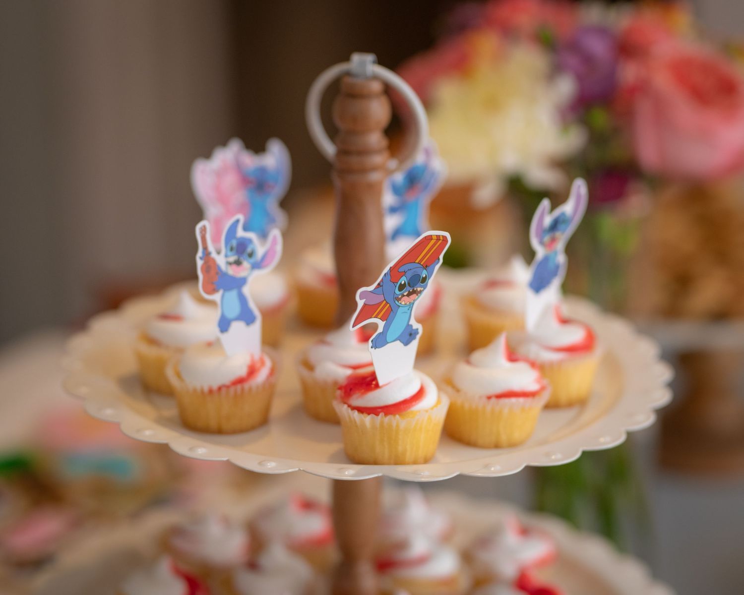 Small decorated cupcakes with red and blue frosting toppers arranged on tiered display stands for a party celebration.