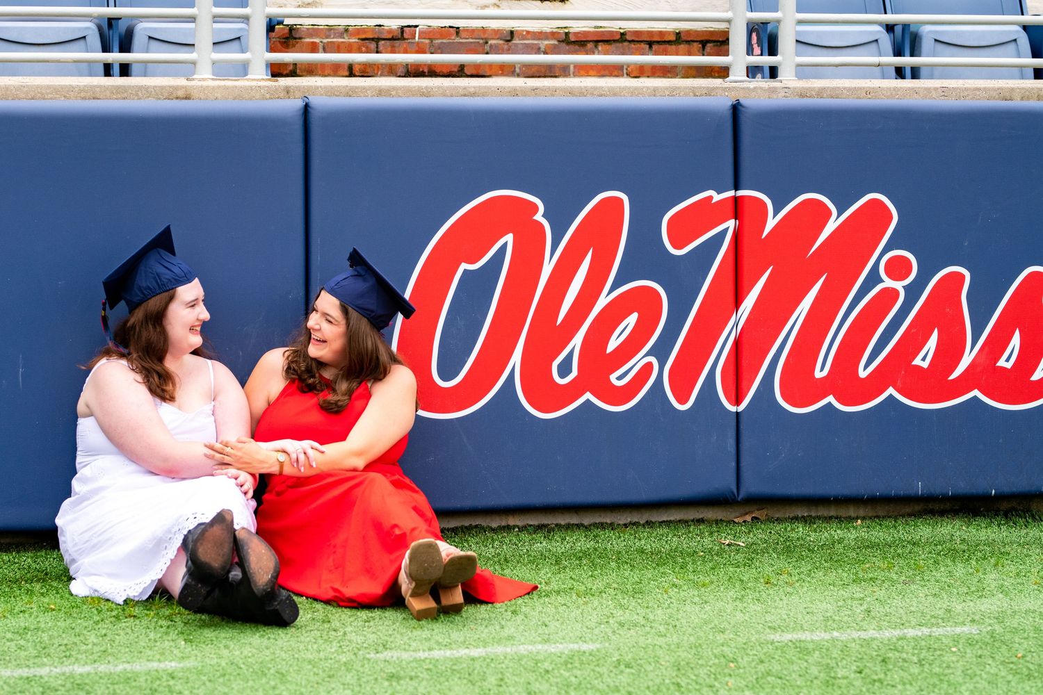 Athletes in red uniforms lay and rest on a sports field with blue signage visible in the background.