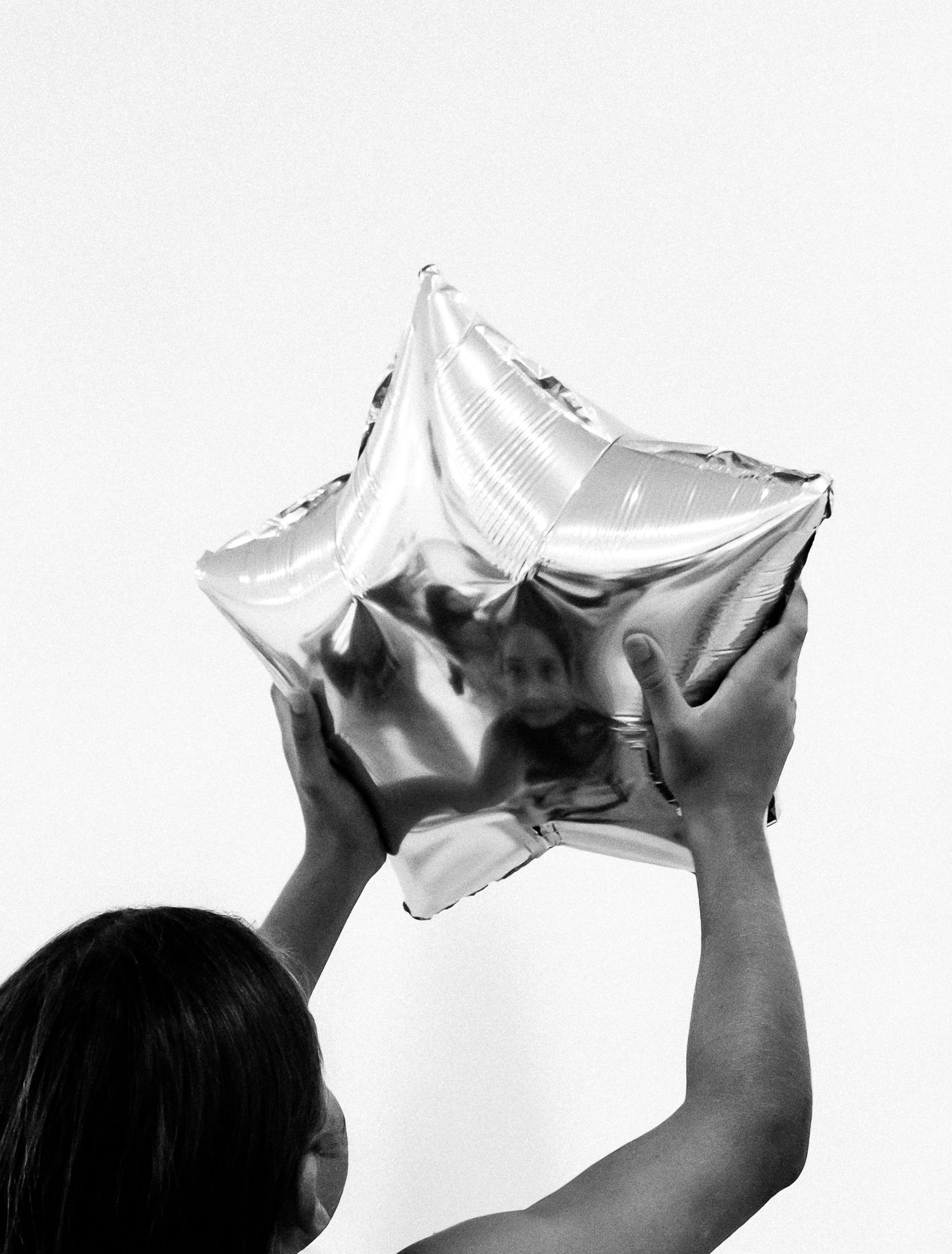 Sequential images of hands stretching and holding a silver metallic material against white background. Photo shot by Mikiah Nicole Dixon