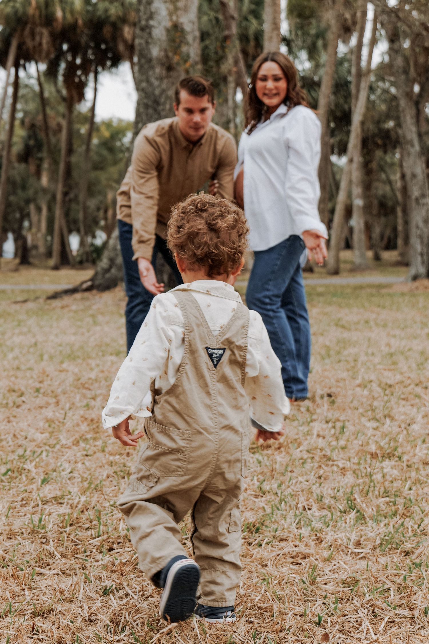 A small child runs through fallen leaves in a wooded area wearing khaki clothing.Photo shot by Mikiah Nicole Dixon