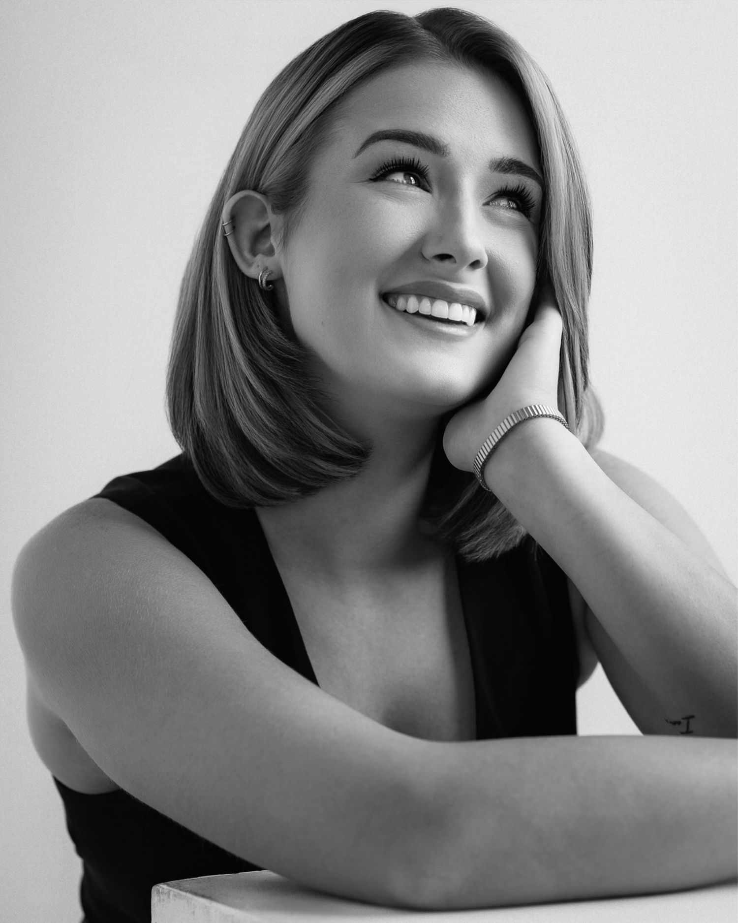 Black and white studio portrait capturing genuine smile and stylish look. Photo shot by Mikiah Nicole Dixon