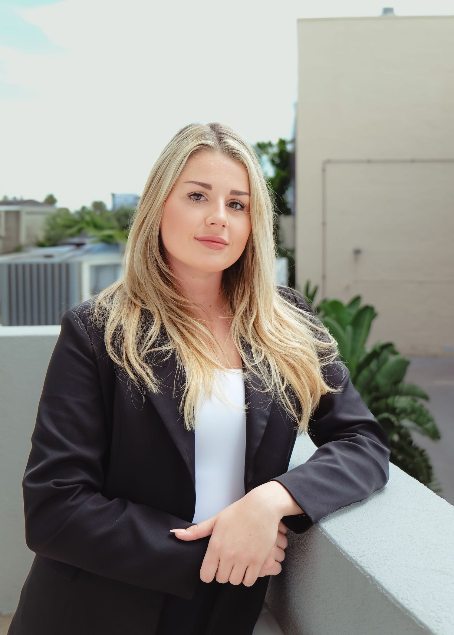 Professional portrait of woman in black blazer on outdoor balcony. Photo shot by Mikiah Nicole Dixon