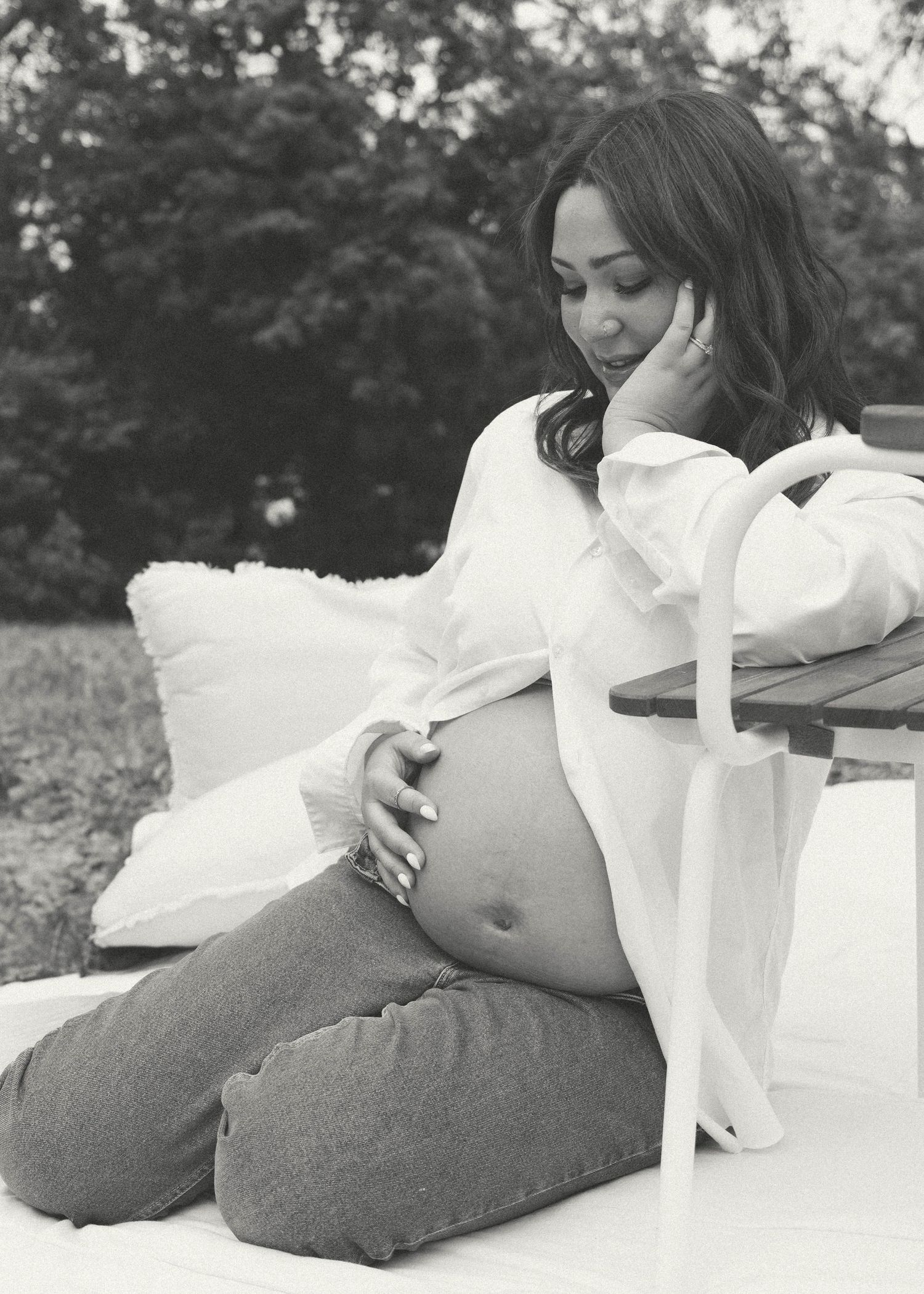 An artistic black and white maternity photo with soft pillows and flowing white fabric. Photo shot by Mikiah Nicole Dixon