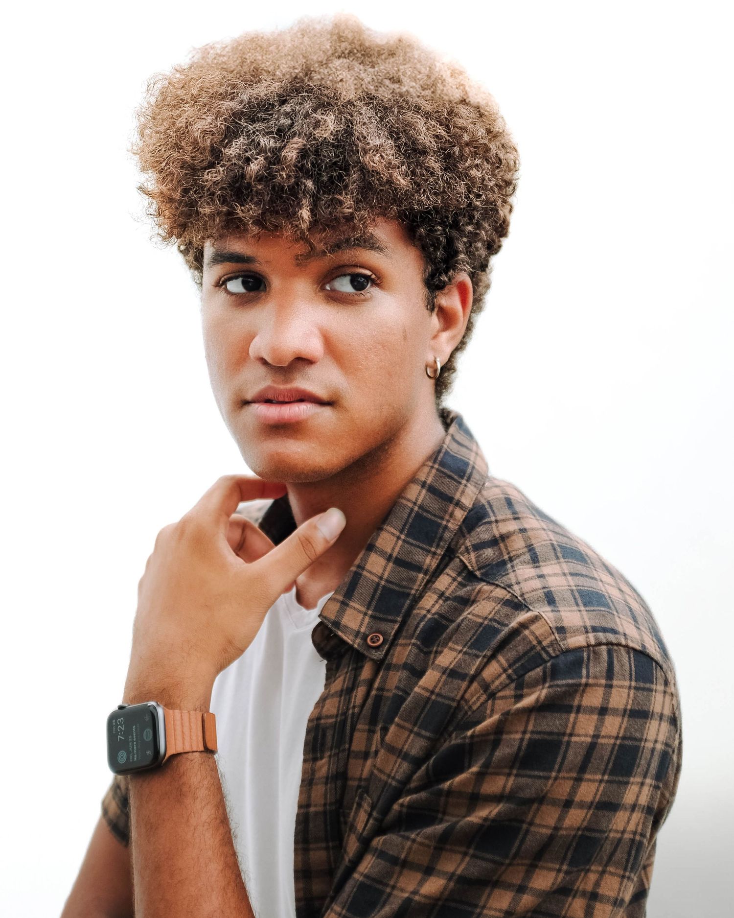 Stylish portrait of young person wearing plaid shirt and smart watch against white background. Photo shot by Mikiah Nicole Dixon