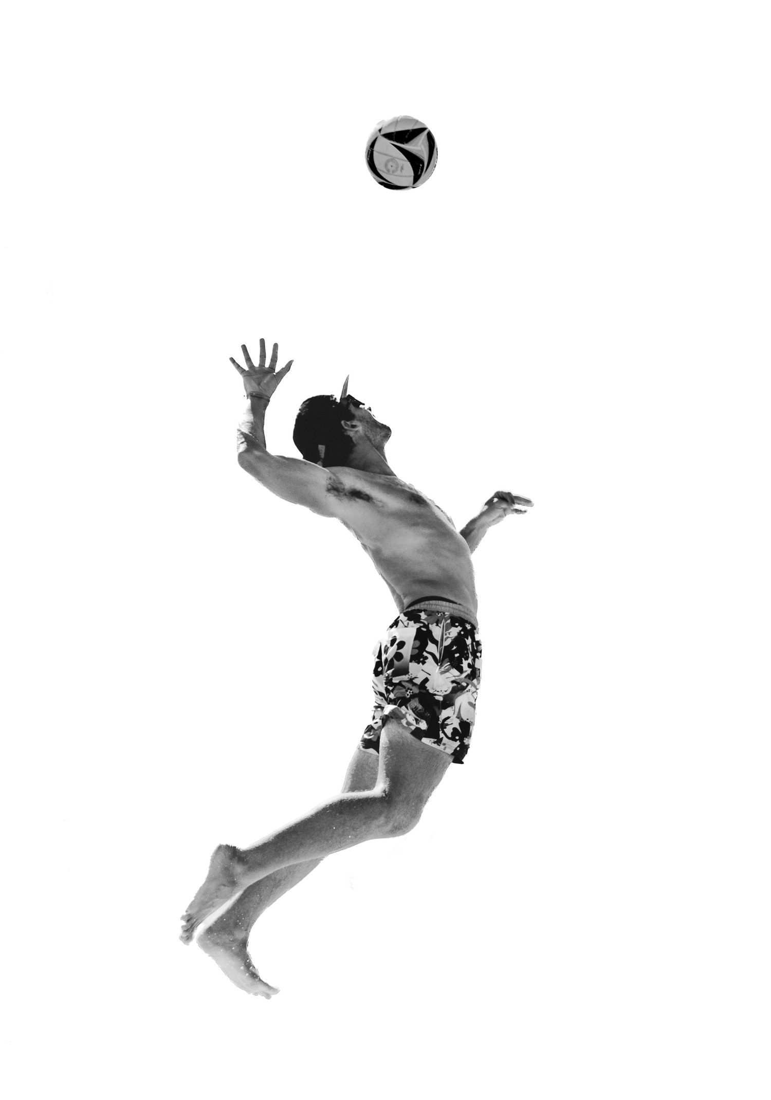 Dynamic black and white shot of volleyball player leaping to reach ball in midair. Photo shot by Mikiah Nicole Dixon